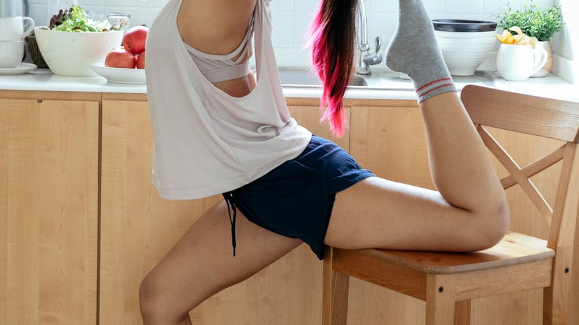 Serene woman in a bright room performing a gentle yoga stretch.